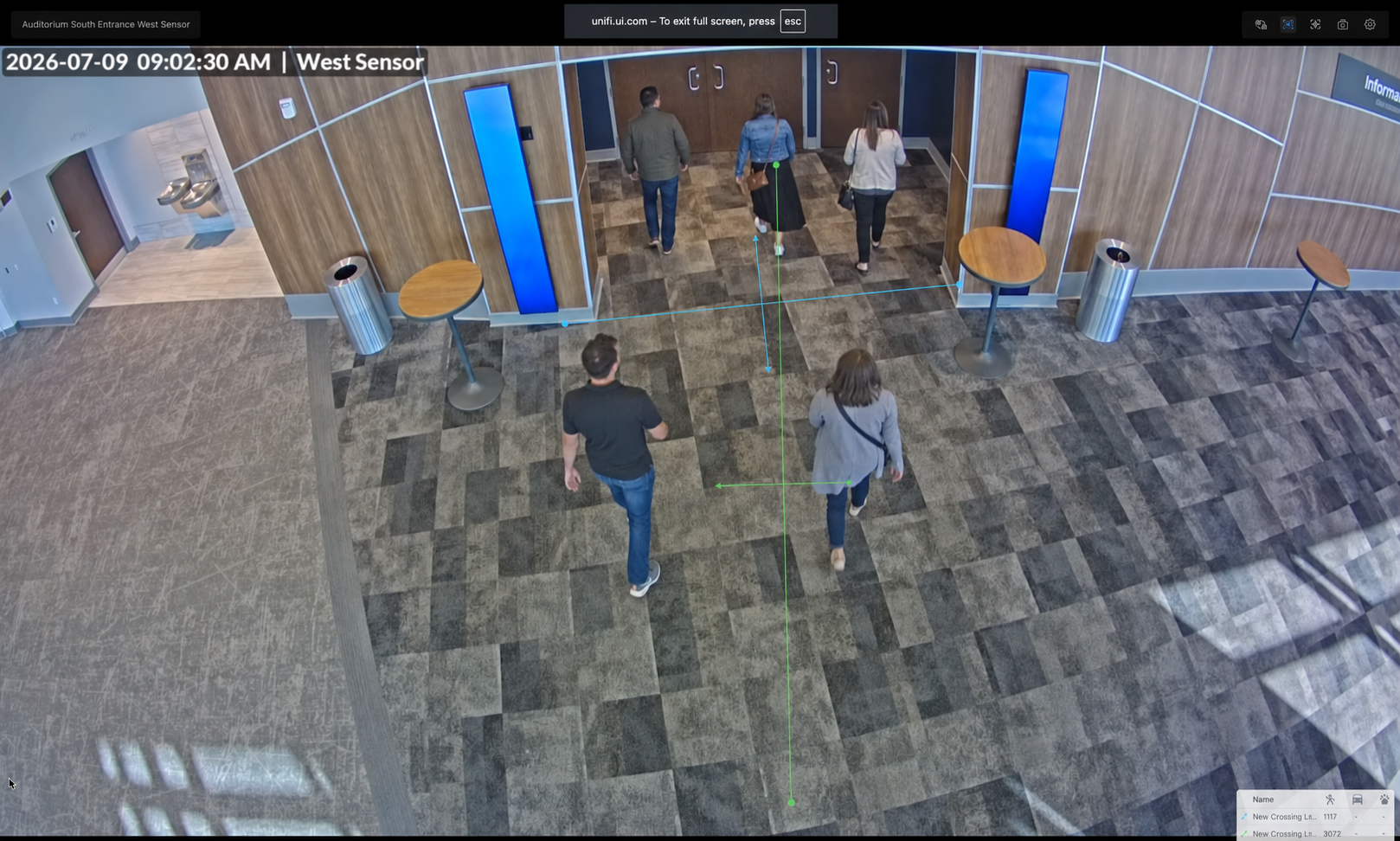 UniFi Protect view of lobby entrance with visitors walking toward doors
